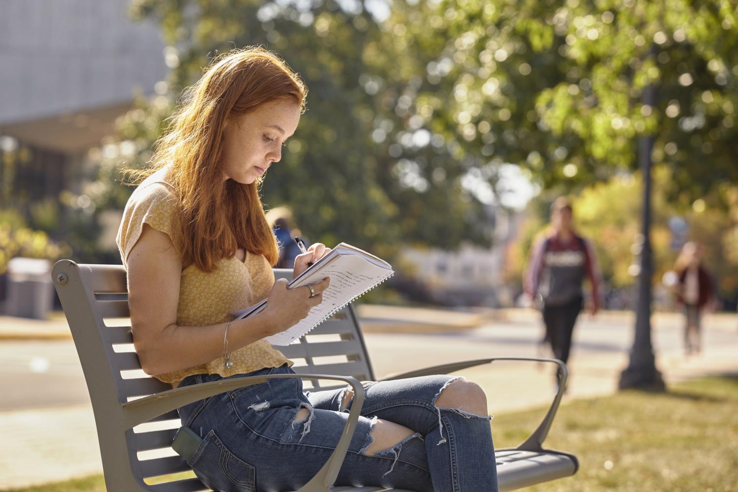 一位<a href='http://491d.uncsj.com'>全球十大赌钱排行app</a>学院的学生在校园里的长椅上读书.